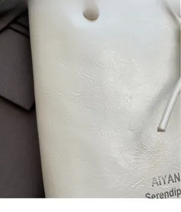 Close-up of creamy white textured leather bucket bag with silver brand logo detail