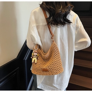 Detail of woven mesh texture on a brown hobo bag with a leather strap and cute charm