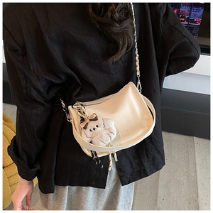 Detailed shot of cream crossbody bag with cute white puppy plush charm and silver chain strap