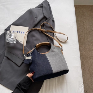 Detail of blue and grey patchwork denim bucket bag with brown faux leather handles and straps