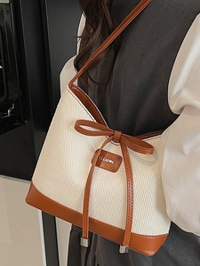 Chic cream straw tote bag with brown leather trim and bow detail for beach vacations