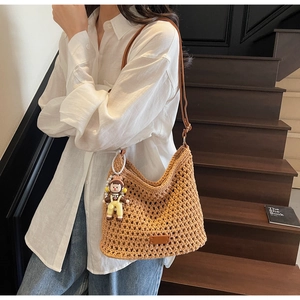 Close-up of brown woven crochet tote bag featuring a cute cartoon doll pendant