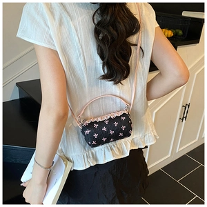 Detail of cylinder mini bag with pink bow embroidery and ruffled trim in lifestyle setting