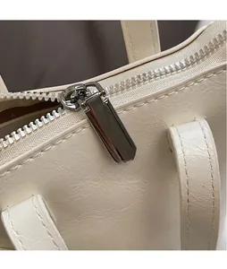 Detailed macro view of the glossy silver metal zipper and lychee pattern on mini bucket bag