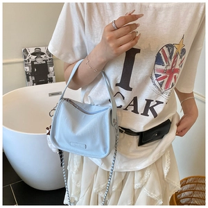 Detail of light blue crossbody bag with pearly texture and metal chain strap