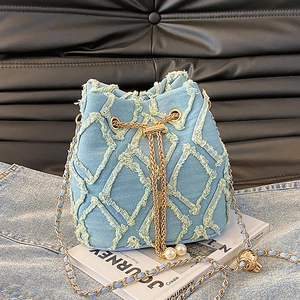 Detail of blue denim bucket bag featuring frayed lattice pattern and pearl charm