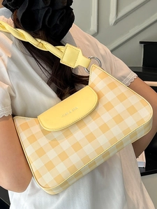 Sac baguette jaune à damier avec bandoulière tressée élégante porté par un mannequin