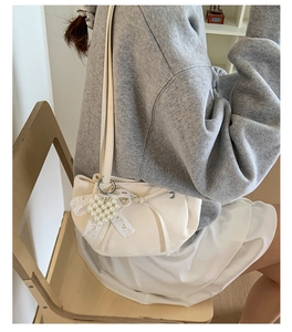 Détail du sac seau blanc crème avec noeud en dentelle et pendentif perle coeur en scène