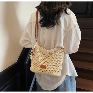 Person wearing beige woven tote bag with brown leather straps and a cute plush charm