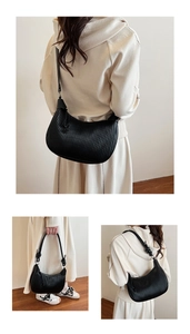 Close-up of black pleated crescent bag with textured vertical folds and knotted strap detail