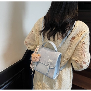 Close-up of a light blue pearlescent backpack with crystal beads and a plush bear charm