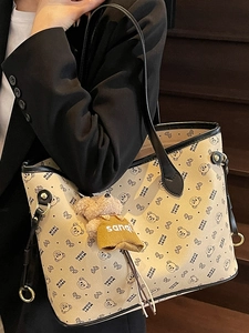 Sac fourre-tout beige avec motif d'ours et charm ours en peluche sur l'épaule du modèle