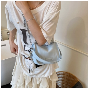 Detail of light blue textured shoulder bag with silver chain strap and plush lamb charm