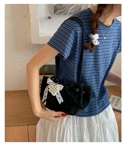 Détail du sac seau en velours noir avec nœud en dentelle et breloque cœur en perles