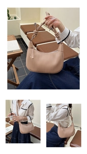 Detail of apricot pleated crescent bag featuring knotted handle and gold metal hardware