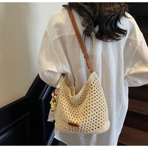 Detail of woven beach tote with brown leather strap and cute character charm accessory