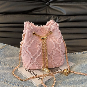 Close-up of pink frayed denim bucket bag with gold chain strap and pearl details
