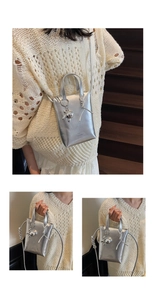 Detail of silver metallic bucket bag with animal charm and woven strap detail