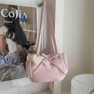 Détail du sac fourre-tout rose clair avec cordon à nœud et accessoire perle et dentelle