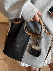 Minimalist patchwork denim bucket bag with brown leather handles and a matching mini charm