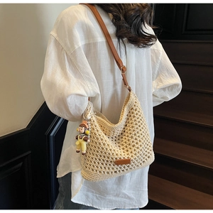 Hobo bag featuring crochet hollow design with a leather strap and cute cartoon pendant