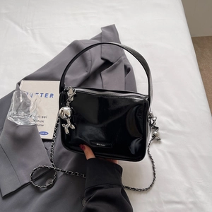 Detail der schwarzen Lackledertasche mit silberner Kette und Ballon-Hund-Anhänger