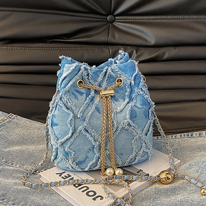 Detailed view of light blue denim bucket bag with frayed quilted pattern and gold chain