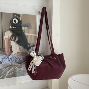 Détail du sac bandoulière en velours bordeaux avec breloque cœur en perles et nœud