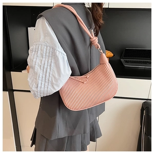 Detail of pink pleated crescent bag with elegant knotted strap on a modern interior background