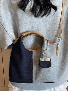 Contrast denim patchwork bucket bag with brown leather straps and mini charm accessory