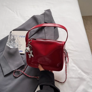 Detail der roten glänzenden Mini-Tasche mit silbernem Ballonhund-Anhänger und Kette