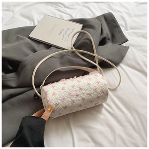 Detailed macro view of white cylinder bag with pink bow pattern and ruffled edge