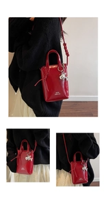 Detail of red glossy mini bucket bag with silver balloon dog charm and knot shoulder strap
