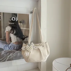 Détail du sac crème avec nœud en dentelle et pendentif cœur en perle de style romantique