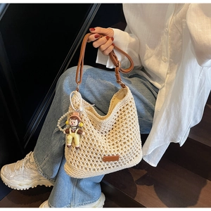 Detail of hand-woven hollow tote bag with brown leather straps and pearl charm
