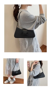 Détail d'un sac baguette tressé noir avec un nœud chic dans un style coréen minimaliste