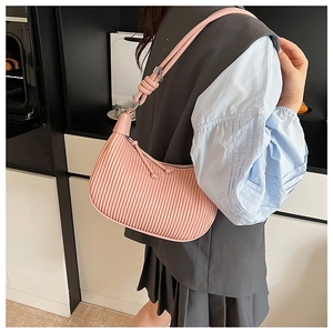 Detail of pink pleated hobo bag with fine shoulder strap and knot decoration on a model