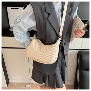 Detail of cream pleated leather texture on a modern bucket bag shown with a model