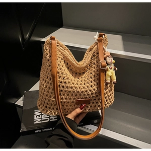 Detail of hand-woven hollow tote bag with brown faux leather strap and cute charm