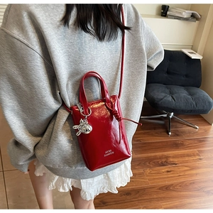 Red patent leather mini bucket bag with silver rabbit charm and logo shoulder strap