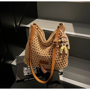 Detail of woven beach tote showing the hollow crochet texture and brown leather strap