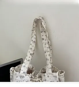 Detailed shot of floral canvas tote bag showing delicate blue flower patterns and handles