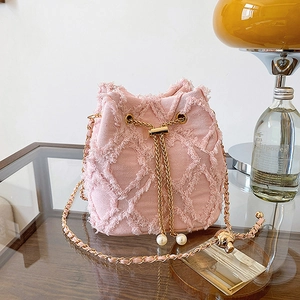 Detailed close-up of pink denim bucket bag featuring frayed edges and pearl drawstring charm