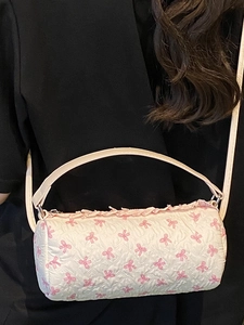 Quilted cylindrical handbag with pink bow patterns and ruffled trim detail