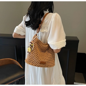Close-up of brown crochet woven beach bag featuring a cute cartoon charm and leather strap