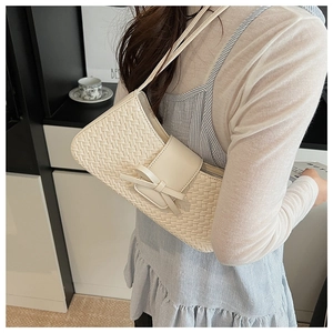 Détail du sac baguette tressé blanc cassé avec un nœud chic et un motif à carreaux