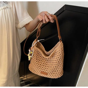 Close-up of hand-woven hollow tote bag with brown leather strap and doll pendant