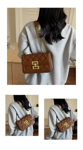 Détail d'un sac bandoulière en cuir matelassé marron avec boucle dorée et chaîne