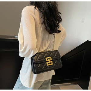 Détail du sac à bandoulière matelassé noir avec un fermoir géométrique doré chic