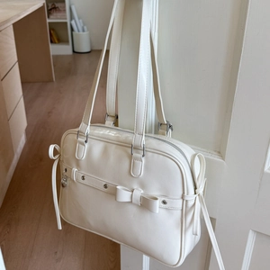 Detail of cream white PU leather backpack with bow accent and silver hardware hanging